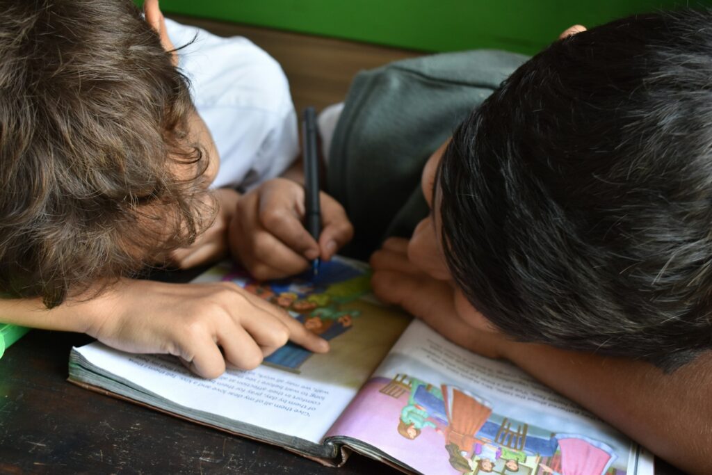 Learning languages early can help these boys communicate while taking notes on their book.