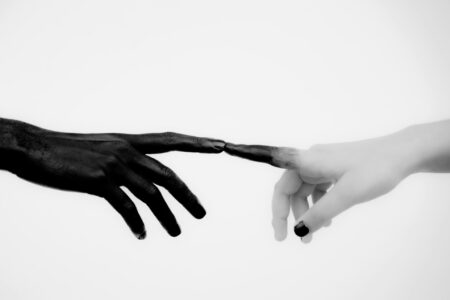 Person 1's painted black hand touching Person 2's painted white hand with black nail polish. Person 2's index finger is turning black due to Person 1's index finger touching them.